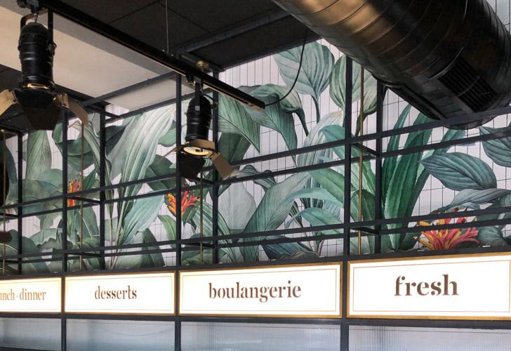 Exotic botanical wallpaper and menu-board wayfinding behind the service area